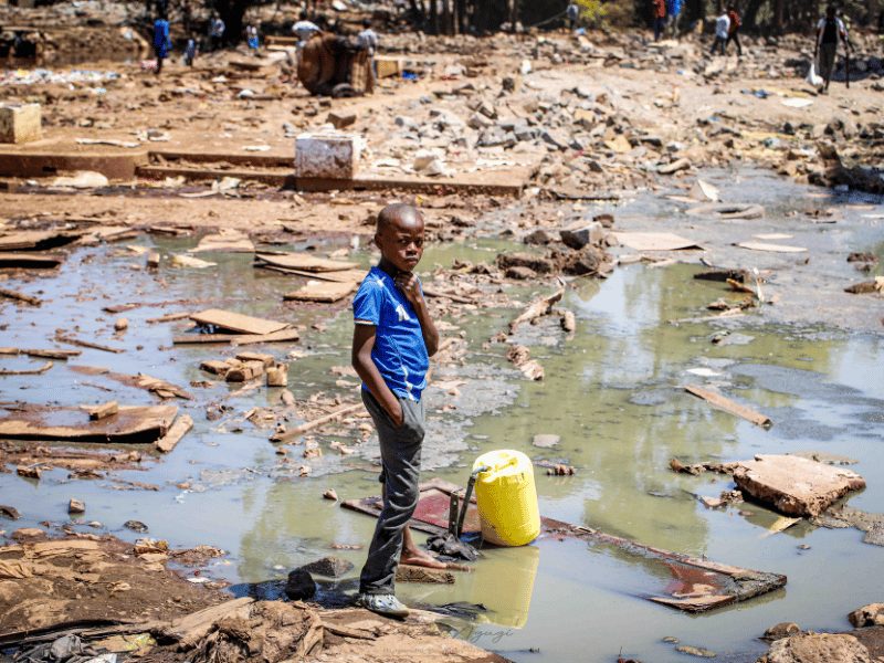 Boy fetches fresh drinking water on a tap in a pool of Sewer water after houses got Demolished in Mathare