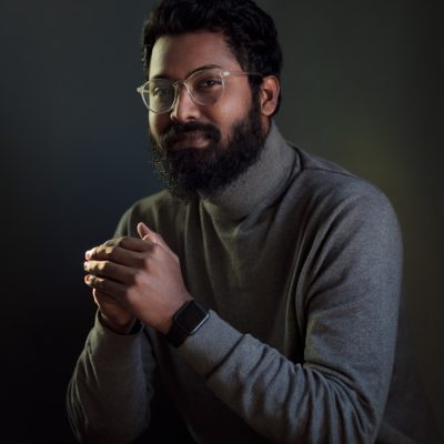 a man with a beard and glasses holding a cigarette