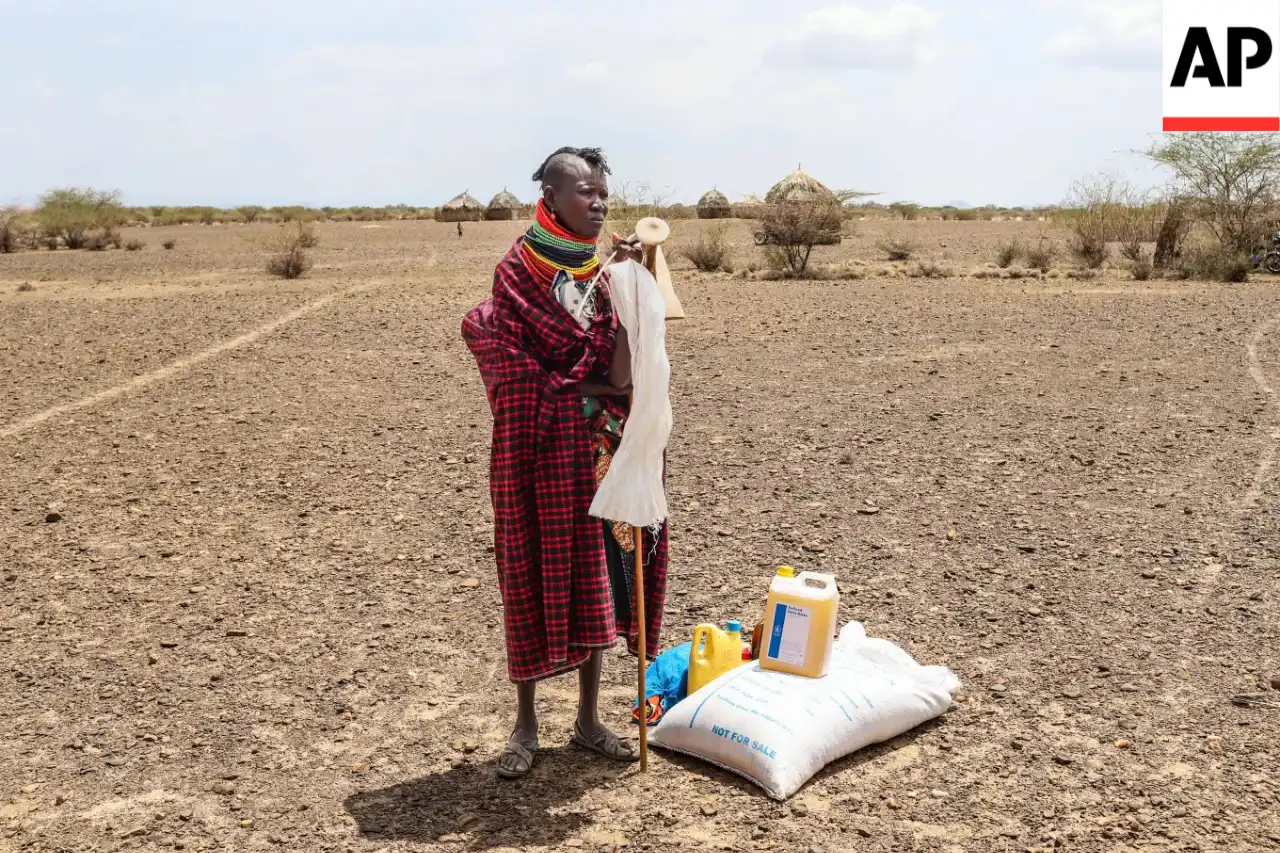 A woman stands beside her food ration after distribution of aid, in Nalemkais Village, Turkana County, Kenya, Sunday, Feb. 8, 2026. (AP Photo/Patrick Ngugi)